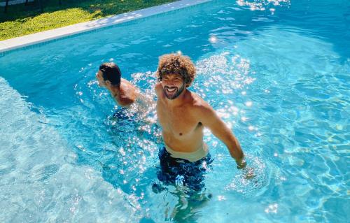 two men playing in a swimming pool at Vila Vale Guest House - Surf & Yoga in Charneca