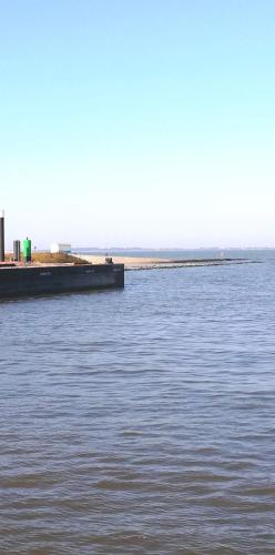 a large body of water with a pier in the distance at Landhaus Löwenzahn in Dornum