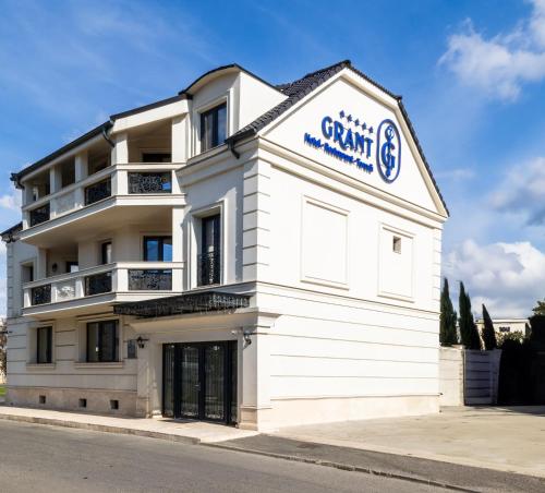 a white building with a sign on the side of it at Grant Boutique Hotel in Arad