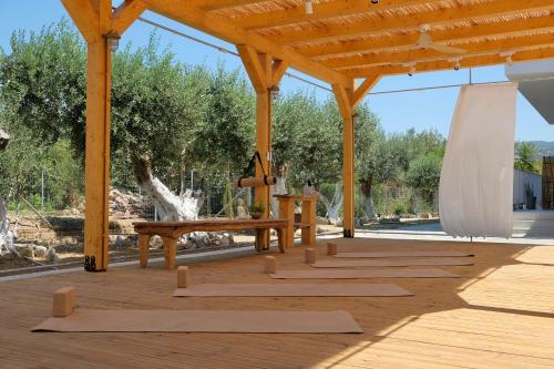 a wooden pavilion with wooden benches and a table at Evia Bay Suites and Retreats in Edipsos
