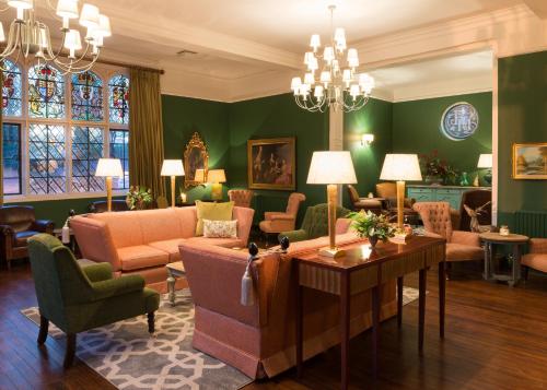 a living room with green walls and a couch and chairs at Burley Manor in Burley