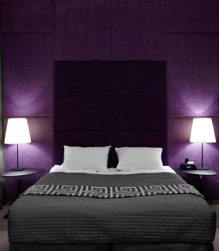 a bedroom with a bed with purple walls and two lamps at Newport in Dnipro