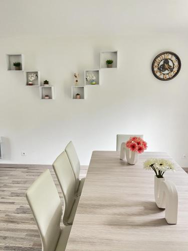 une salle à manger avec une table, des chaises et une horloge dans l'établissement Maison spacieuse de Lila avec 3 places de parkings, à Crèvecoeur-le-Grand