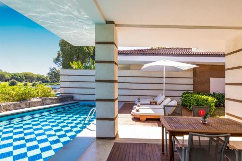 an outdoor patio with a table and a swimming pool at Kempinski Hotel The Dome Belek in Belek