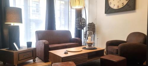 a living room with a chair and a table and a clock at La maison GUILLAUME in Falaise