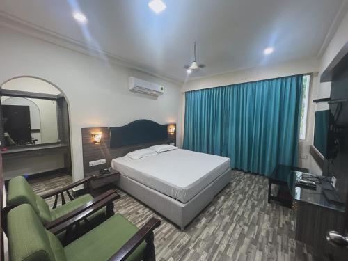 a bedroom with a bed and two chairs and a television at Varada nagavali hotel in Srīkākulam