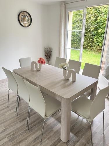 une table à manger avec des chaises et une horloge murale dans l'établissement Maison spacieuse de Lila avec 3 places de parkings, à Crèvecoeur-le-Grand