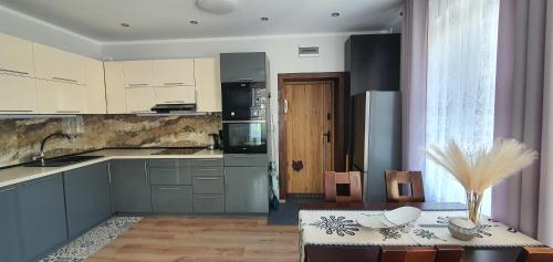 a kitchen with gray cabinets and a table with a table sidx sidx sidx at APARTAMENT MAJA - centrum, parking in Kudowa-Zdrój