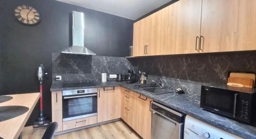 a kitchen with wooden cabinets and a clock on the wall at La maison GUILLAUME in Falaise