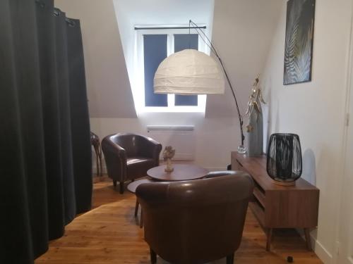 a living room with a table and a chair at La maison GUILLAUME in Falaise