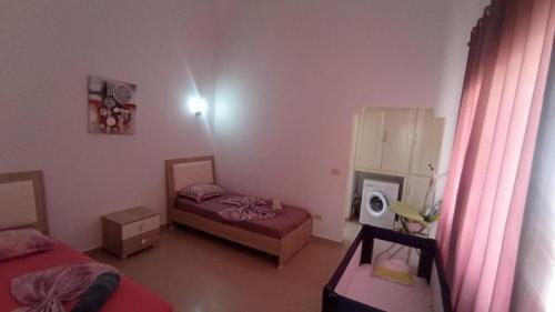 a small bedroom with two beds and a window at Villa standing avec piscine privée sans vis à vis et WiFi à Djerba in Fafou