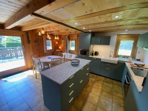 une cuisine avec des armoires vertes et une table ainsi qu'une salle à manger dans l'établissement Chalet Orval - Chamonix Argentiere, à Chamonix-Mont-Blanc