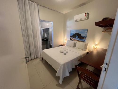 a bedroom with a bed and a desk and a window at Pousada Kalunga in Flecheiras