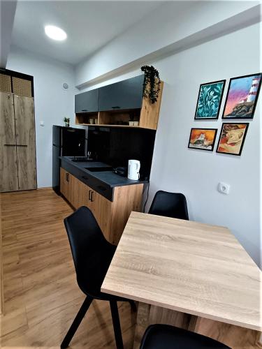 a kitchen with a wooden table and black counters at Apartman Vista Centar in Smederevo