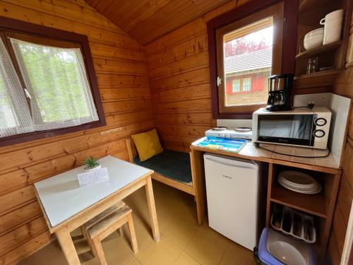 a kitchen with a microwave and a table in a cabin at Camping de Saulieu in Saulieu