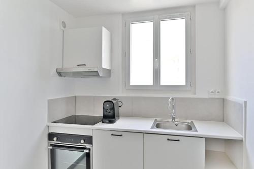 une cuisine blanche avec un évier et une fenêtre dans l'établissement Studio fashion Proche Métro #Paris #Montreuil - II, à Montreuil