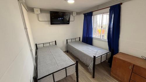 a small room with two beds and a window at Amanecer Serrano Carlos Paz in Villa Carlos Paz