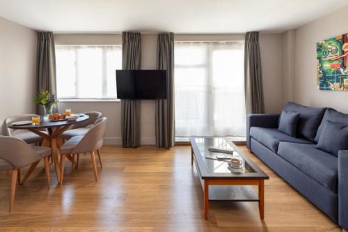 a living room with a blue couch and a table at Marlin Apartments Commercial Road - Limehouse in London
