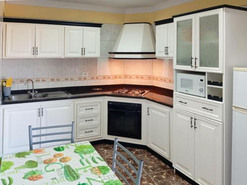 a kitchen with white cabinets and a table and a microwave at Live la Victoria Carril in La Victoria de Acentejo