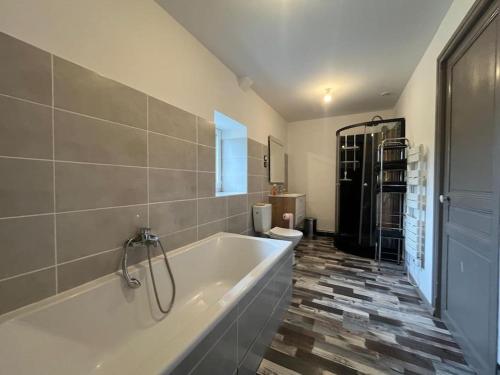 La salle de bains est pourvue d'une baignoire et de carrelage. dans l'établissement Maison des Marais des Souvenirs, à Orglandes