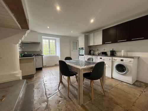une cuisine avec une table et des chaises ainsi qu'un lave-linge dans l'établissement Maison des Marais des Souvenirs, à Orglandes