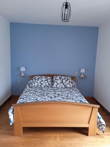 une chambre avec un lit avec un mur bleu dans l'établissement Ty Samy et Seb, à Mauron