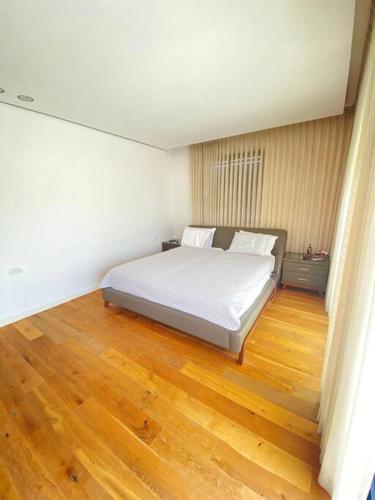 a bedroom with a white bed and a wooden floor at Villa on the beach in Netanya