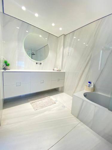 a white bathroom with a tub and a mirror at Villa on the beach in Netanya