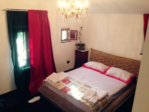 a bedroom with a bed with red curtains and a chandelier at Fashion House Tuscany ARTIMINO in Artimino