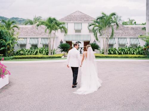 a bride and groom standing in front of a mansion at Round Hill Hotel & Villas in Montego Bay