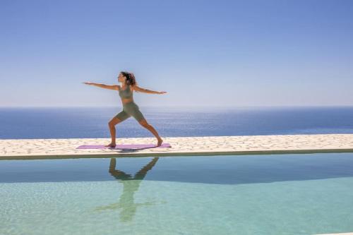 a woman is standing on a surfboard in the water at Skali Retreat in Atsoupádhes