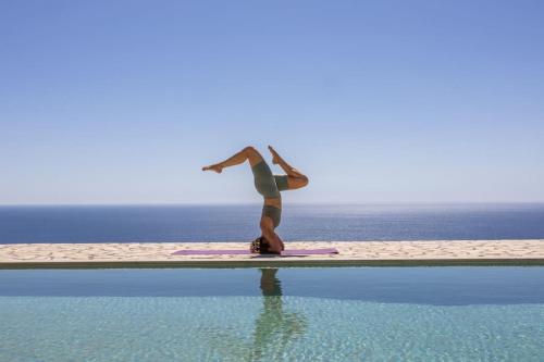 a woman standing on a surfboard next to a swimming pool at Skali Retreat in Atsoupádhes