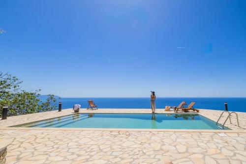a woman standing next to a swimming pool next to the ocean at Skali Retreat in Atsoupádhes