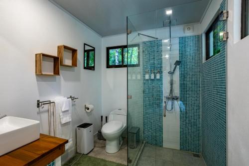 a bathroom with a toilet and a glass shower at Casa Serena - Tranquil Jungle Gem Near the Beach in Uvita