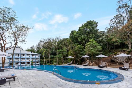 a pool at a resort with chairs and umbrellas at Sterling Munnar in Munnar