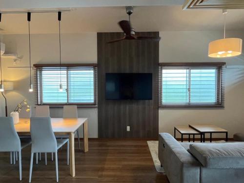 a living room with a table and a couch at Kin-Con-Kan 1F 新築 那覇空港から車で25分 南部観光に最適 広々80平米 コンビニ徒歩1分 沖縄ワールド徒歩9分 最大9人 in Nanjo