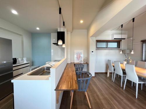 a kitchen and dining room with a table and chairs at Kin-Con-Kan 1F 新築 那覇空港から車で25分 南部観光に最適 広々80平米 コンビニ徒歩1分 沖縄ワールド徒歩9分 最大9人 in Nanjo
