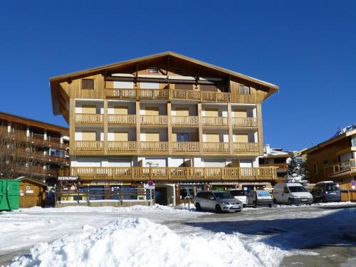 un grand bâtiment en bois avec des voitures garées dans un parking dans l'établissement Studio 4 pers. 23m² - Centre, Télécentre, Animaux OK, Terrasse Sud - FR-1-405-182, à L'Alpe-d'Huez
