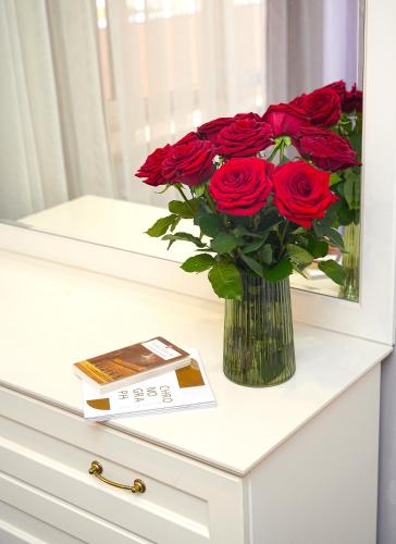 a vase filled with red roses sitting on a table at Sweet Home Apart-Hotel in Yerevan