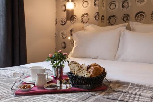 a breakfast tray with bread and pastries on a bed at Le Mireille in Paris