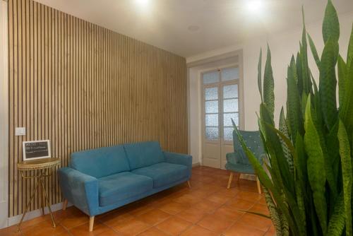 a living room with a blue couch and a plant at Residencial Fortunato in Ericeira