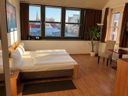 a bedroom with a bed in a room with windows at Hotel Am Hopfenmarkt in Rostock