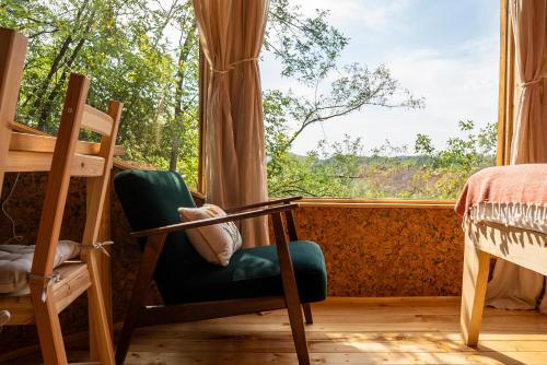 a bedroom with a chair and a large window at La sat - Ană Năzdrăvană in Bertea