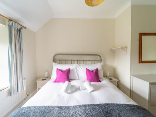 a bedroom with a white bed with pink pillows at Pass the Keys Unicorn Cottage Rural Cotswold Escape in Great Rollright