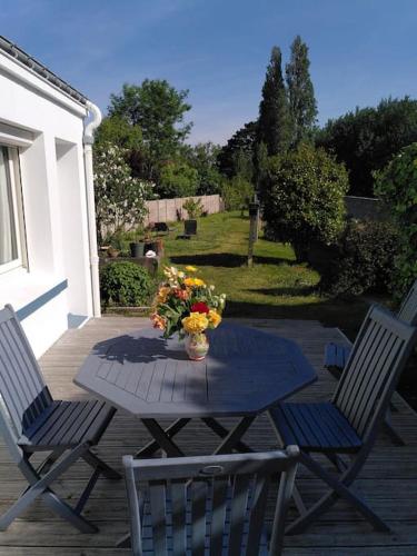 - une table avec un vase de fleurs sur la terrasse dans l'établissement Maison de pêcheur avec jardin à 100m de la petite mer de Gâvres, à Riantec