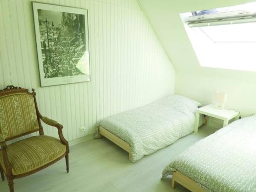 - une chambre avec un lit, une chaise et une photo dans l'établissement Maison de pêcheur avec jardin à 100m de la petite mer de Gâvres, à Riantec