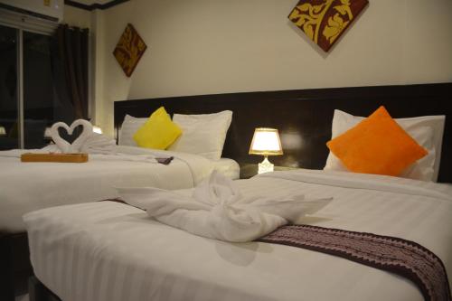 two beds with white towels on them in a bedroom at Patong Moon Inn Residence in Patong Beach