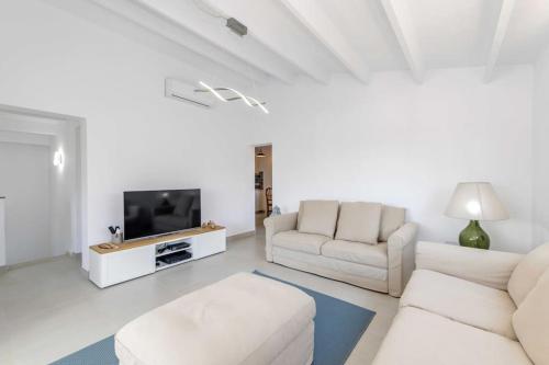 a living room with white furniture and a flat screen tv at Villa Mare a fabulous hideaway in S'Algar