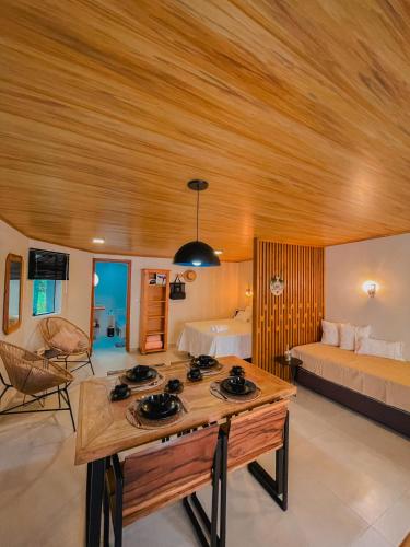 a room with a wooden ceiling and a bed and a table at Shangri La Casas e Studios in Praia do Rosa