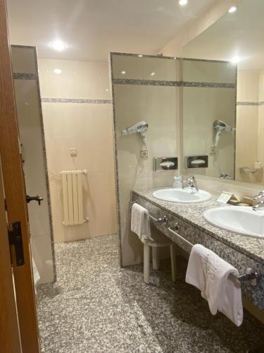 a bathroom with two sinks and a large mirror at Parador de Vilalba in Villalba